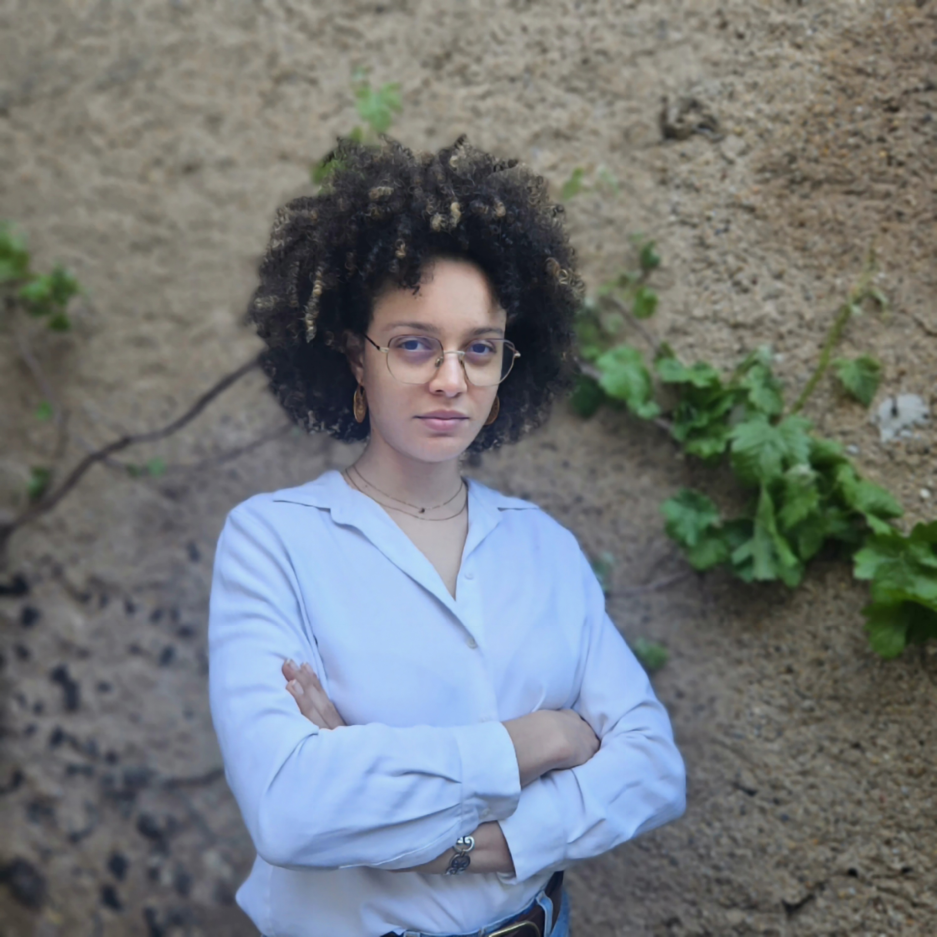 Portrait de Naomi, fondatrice de NaoWin, devant un mur en pierre de l'Hérault entouré de vignes